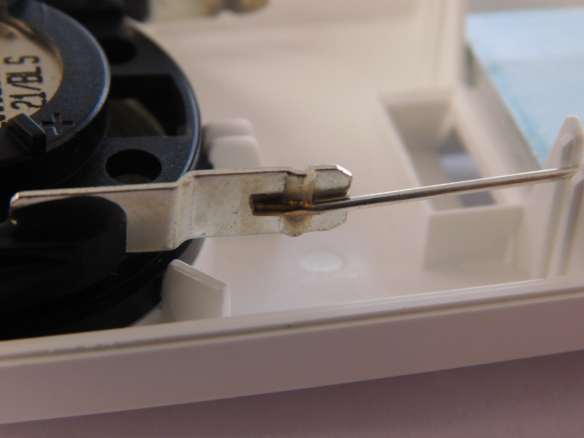 Battery contact spring welded onto a stamped terminal inside a consumer device housing — clean micro-weld with minimal heat impact on surrounding plastic.