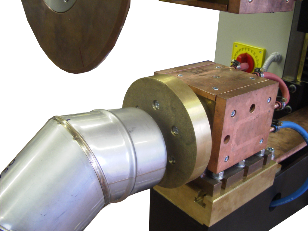 Chimney elbow positioned on the dedicated tooling — resistance seam welding produces a continuous, gas-tight joint along the curved geometry.